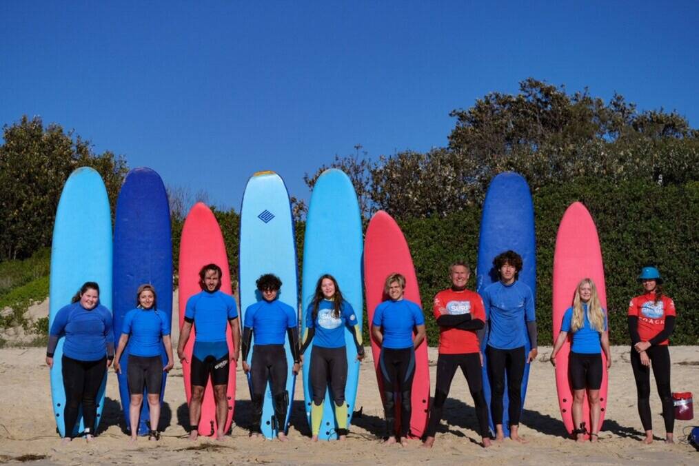 A group of surfers with surfboards on the beach