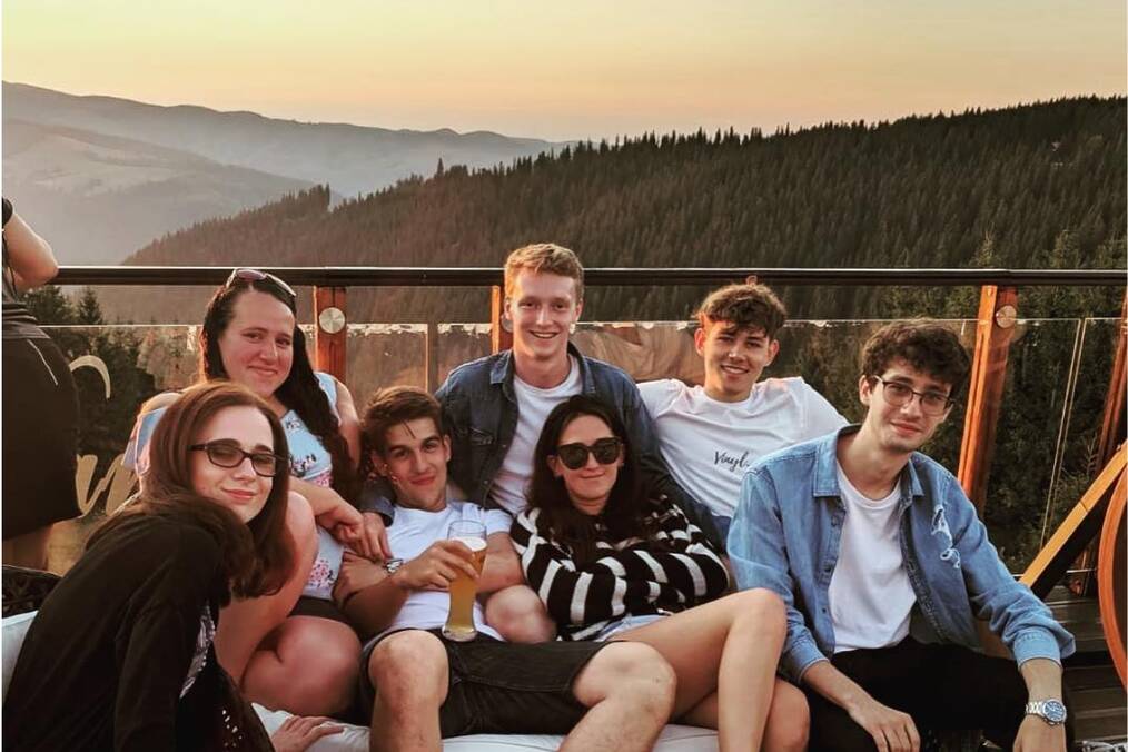 A group of friends in front of a mountainous backdrop during sunset