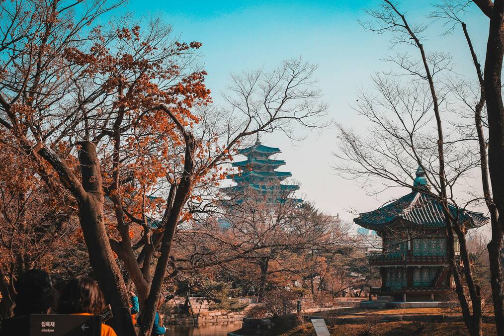 An Asian palace surrounded by trees under a blue sky 