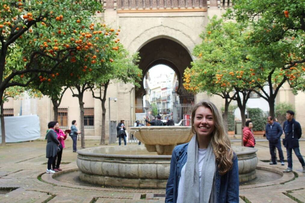A person posing in front of a fountain in Spain
