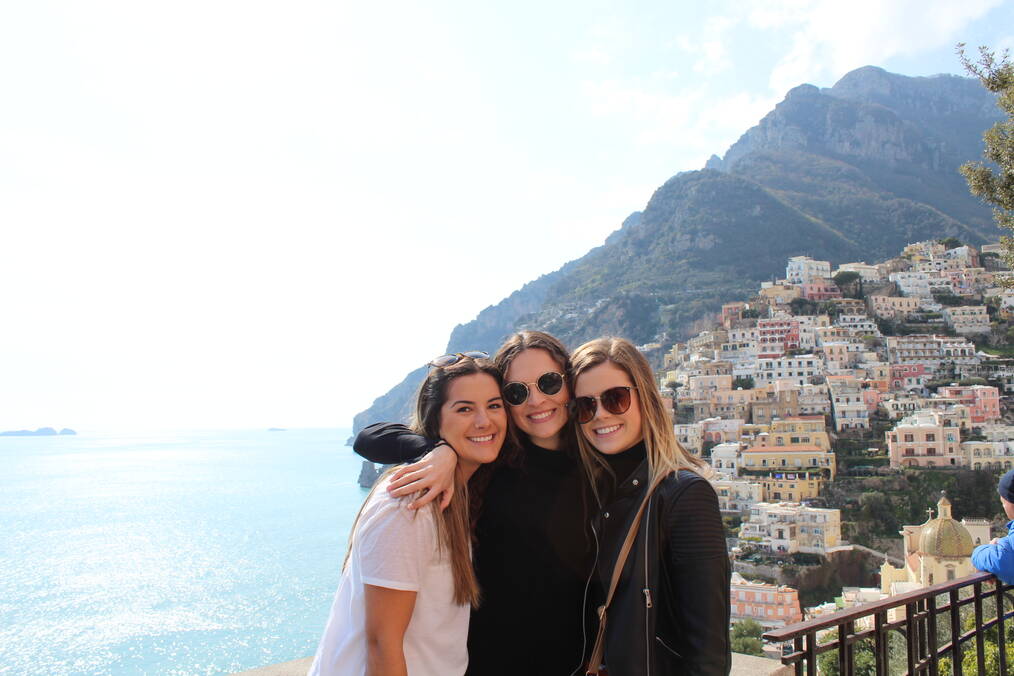 Three friends standing next the sea in a coastal town