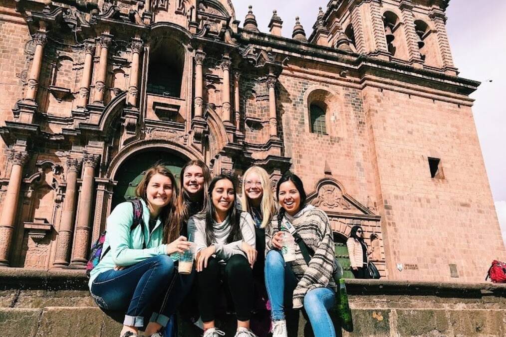Five women sitting in front of a historic building in Ecuador.