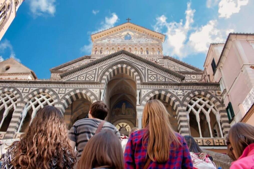 A group of people walking up the stairs to a religious building 