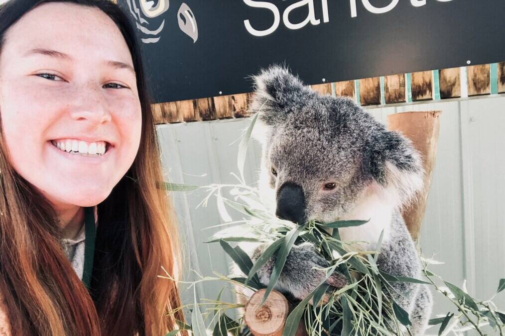 A person smiling next to a Koala 