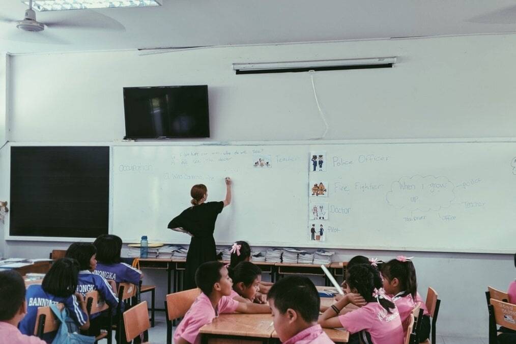 A teacher writing on the whiteboard of a classroom