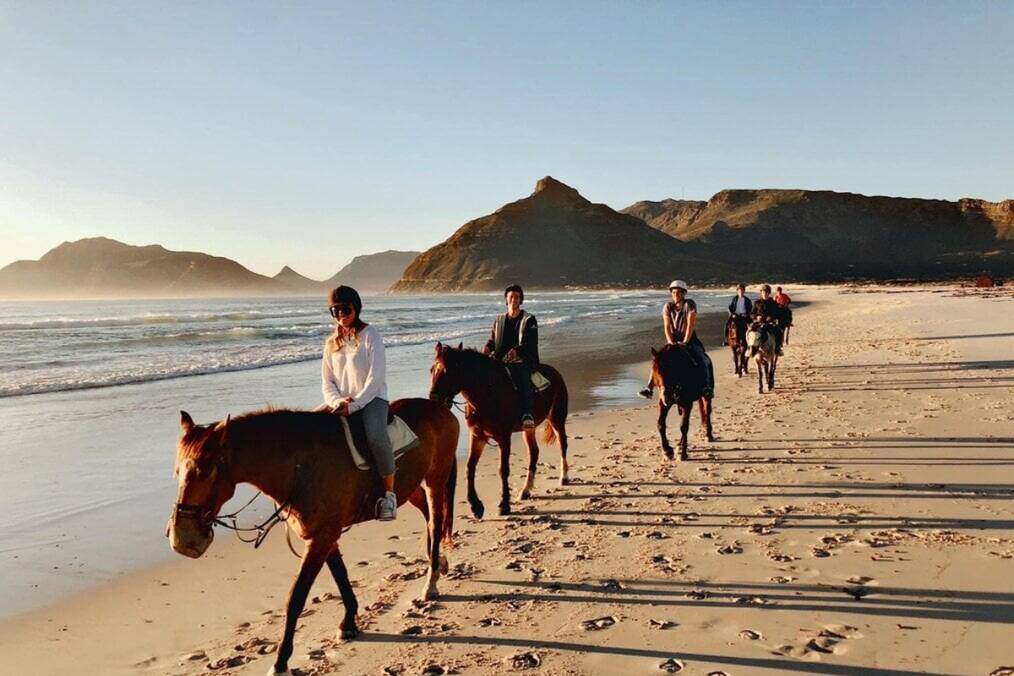 A group of people horseriding on a beach