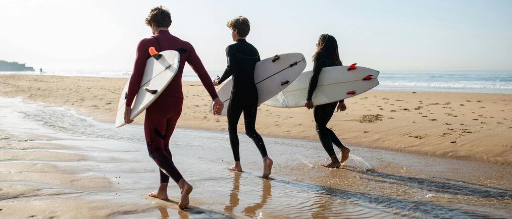 friends walking on the beach with surfboards