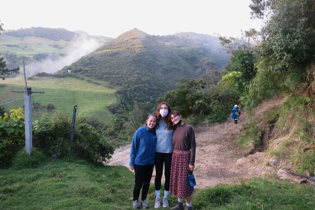 Three people standing in the rolling hills of Ecuador