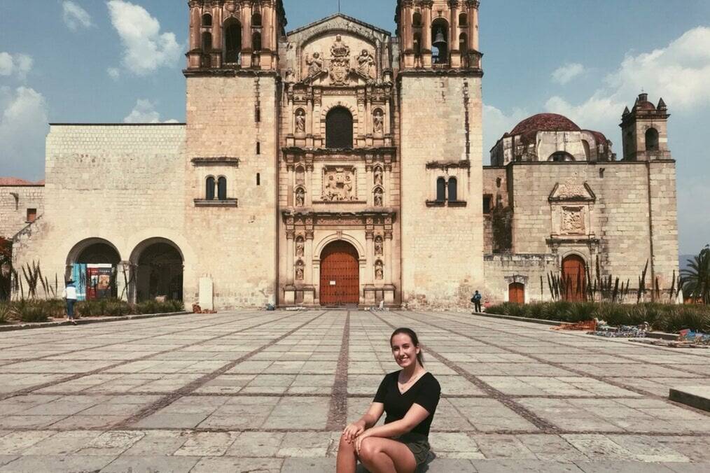 A girl sat in front of an old Mexican cathedral