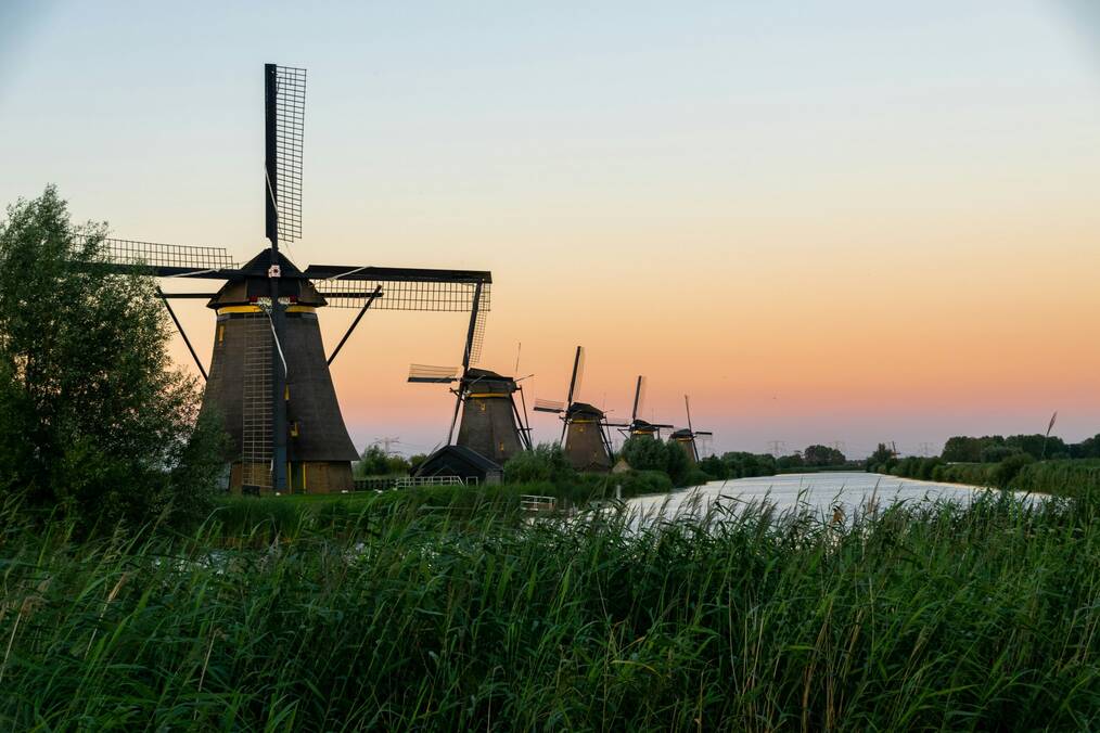 Windmills next to a canal at sunset