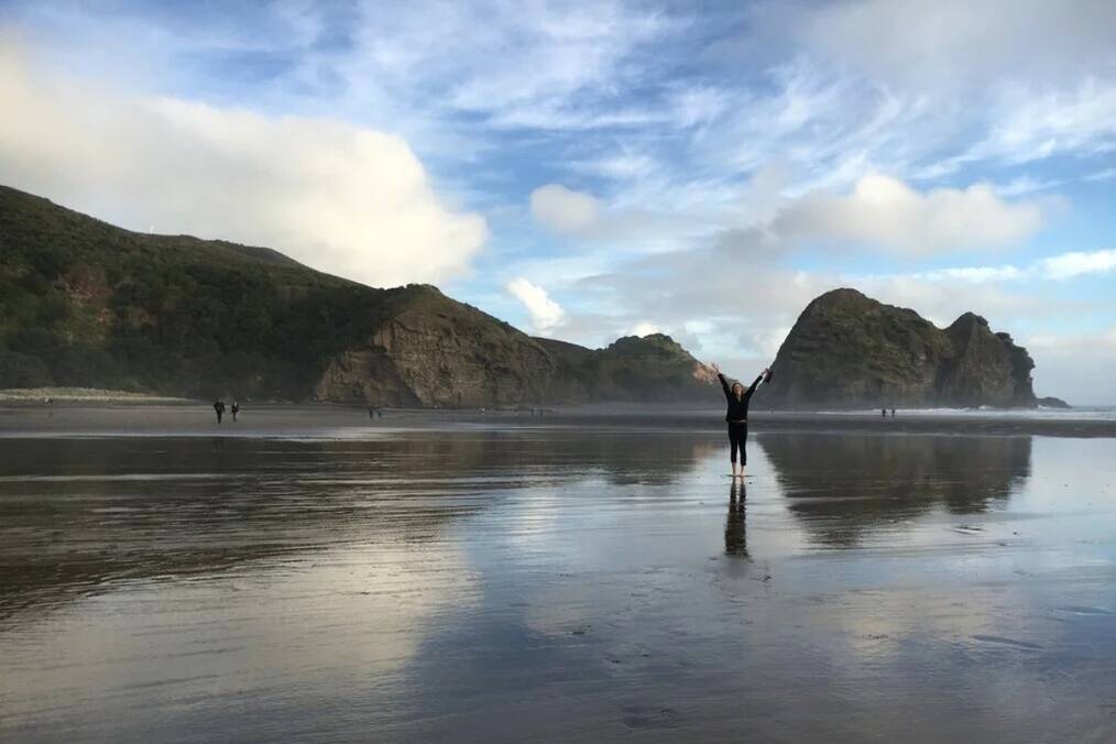 A person standing on a reflective beach 