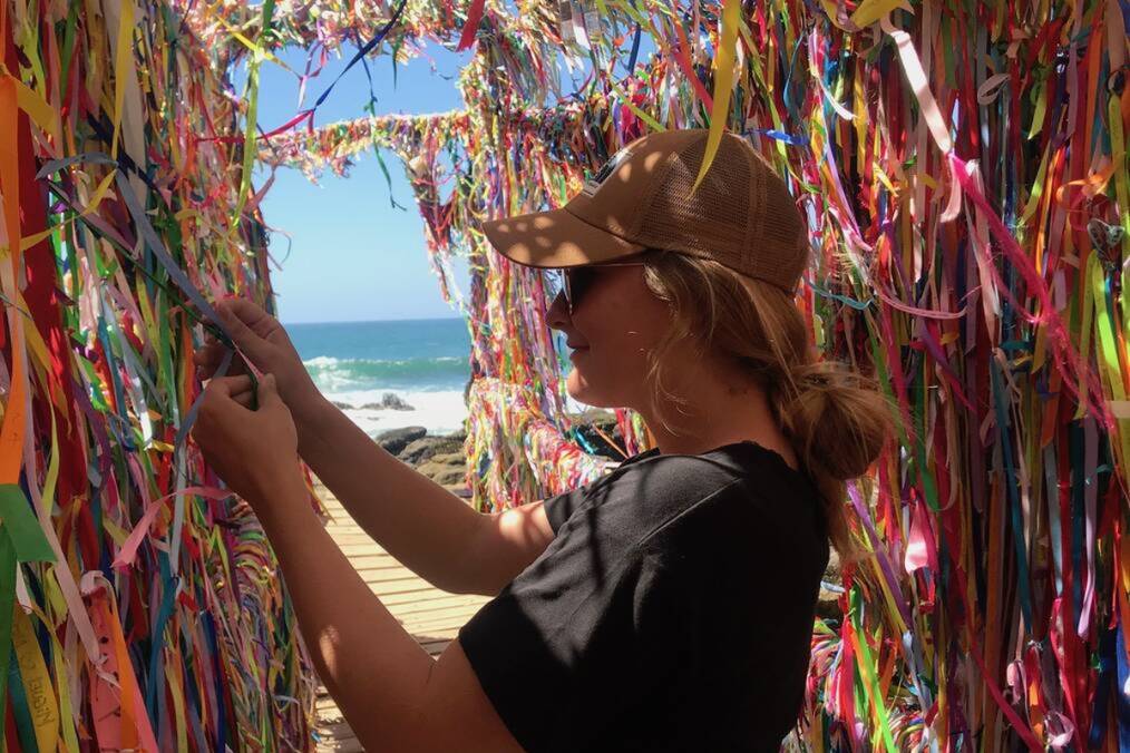 A person inspecting colorful ribbons at the beach