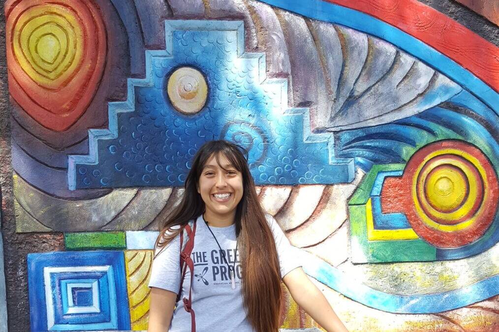 A person standing in front of a colorful mural 