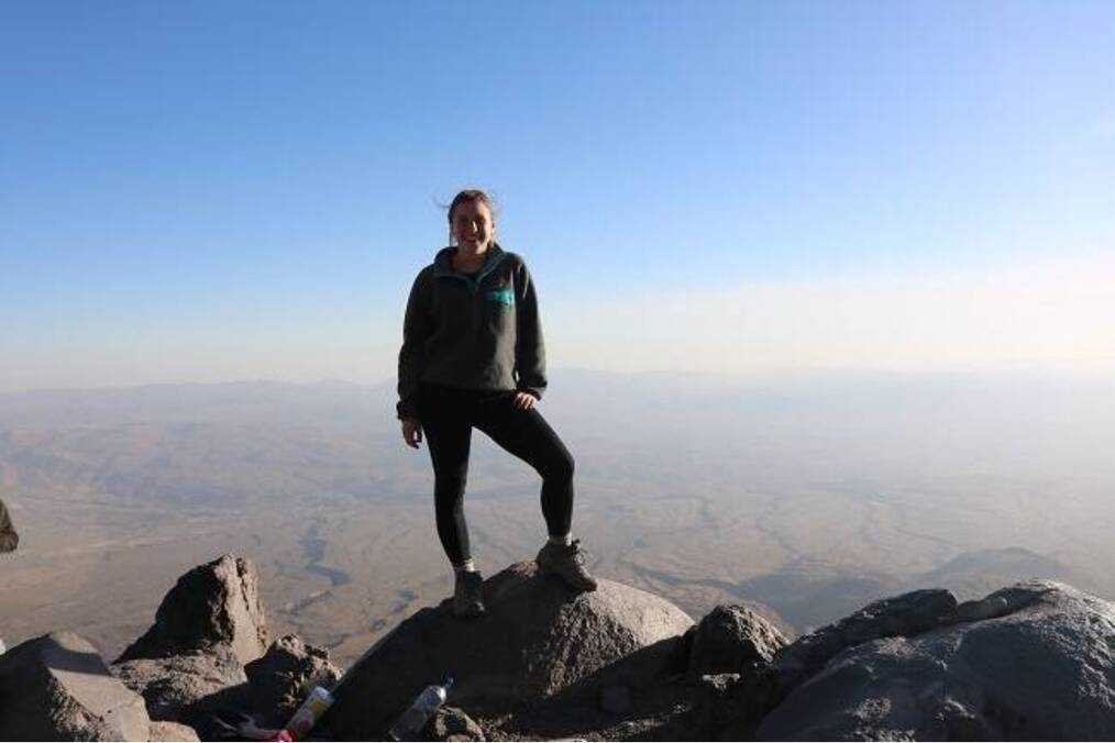 A person standing on top of a mountain with a scenic backdrop