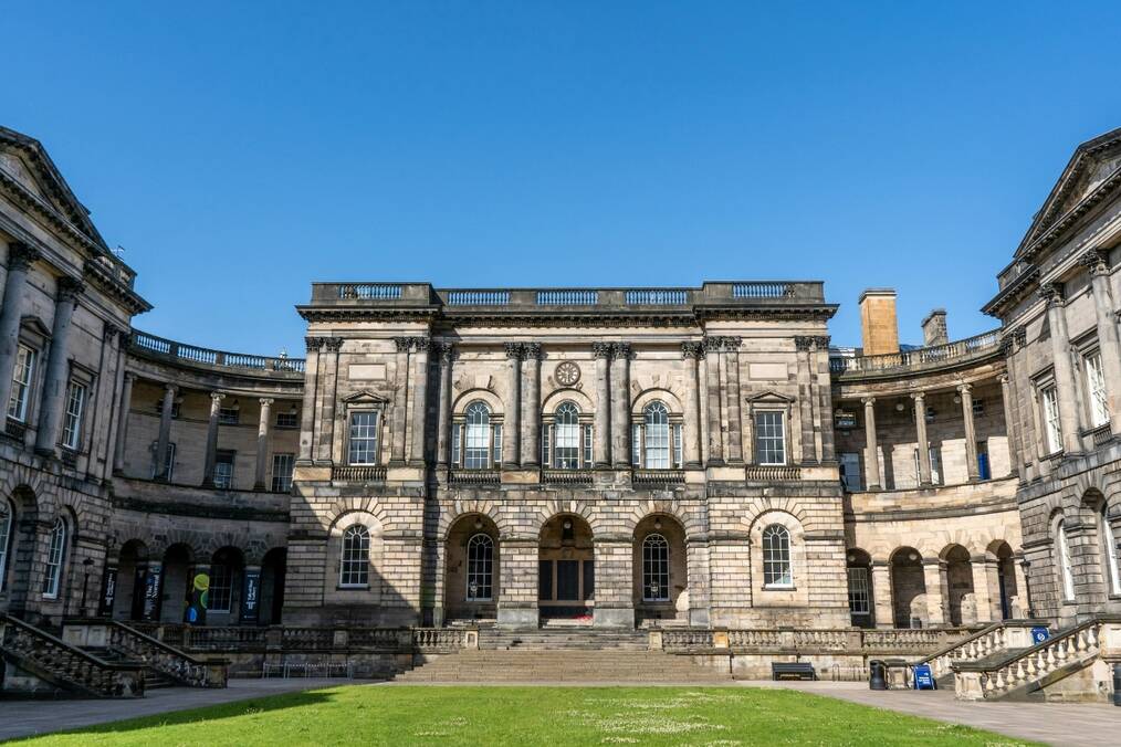 An old university building with a patch of grass on a sunny day