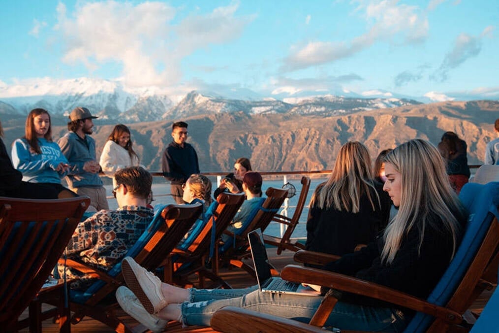 A group of people on top of a boat surrounded by mountains