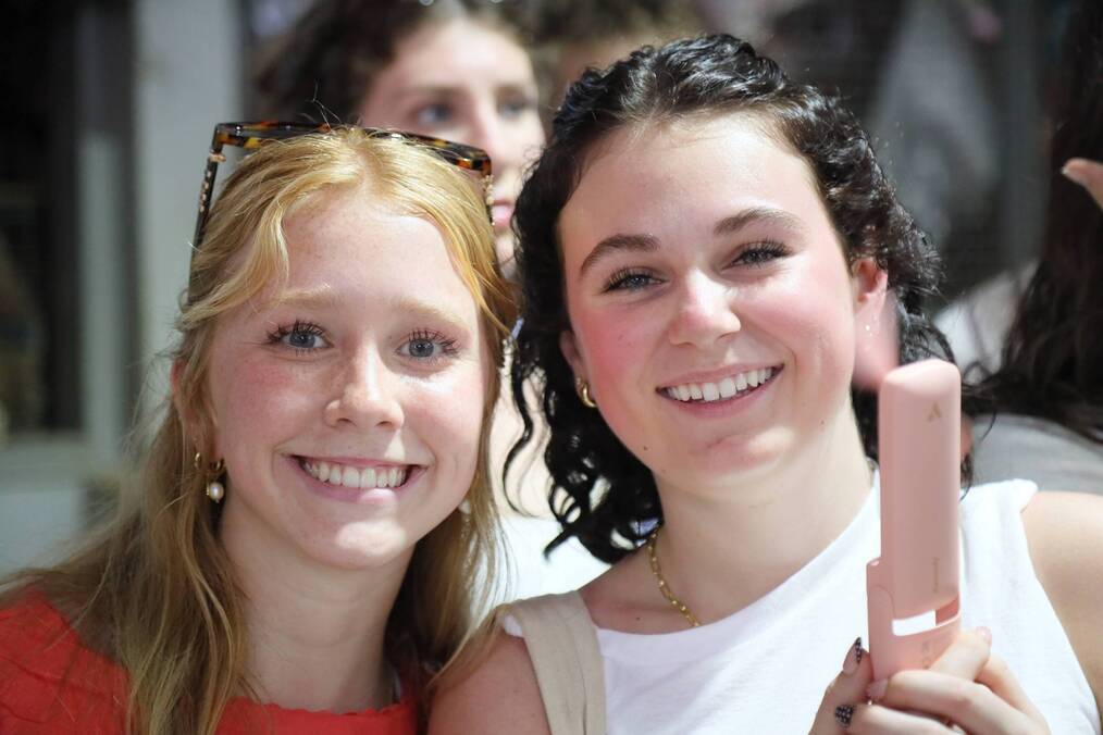 Two students smiling and holding a fan