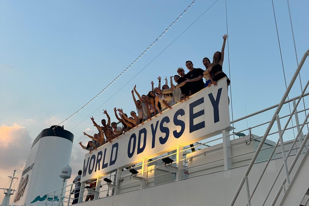 Semester at Sea students raising their hands up and smiling on the ship