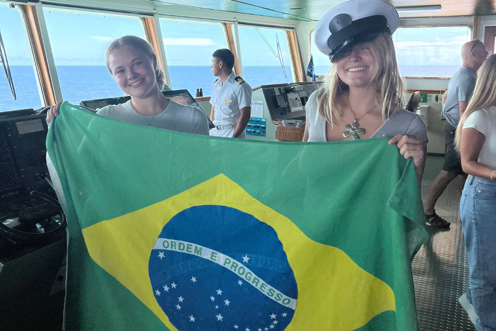Two students smiling and holding up the Brazil flag