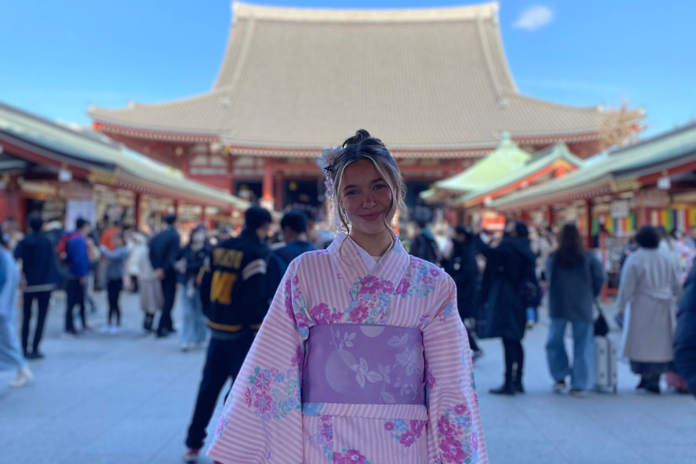 A Beyond Academy intern wears a pink floral kimono in front of Sensoji Temple in Asakusa, Tokyo, with crowds of visitors in the background