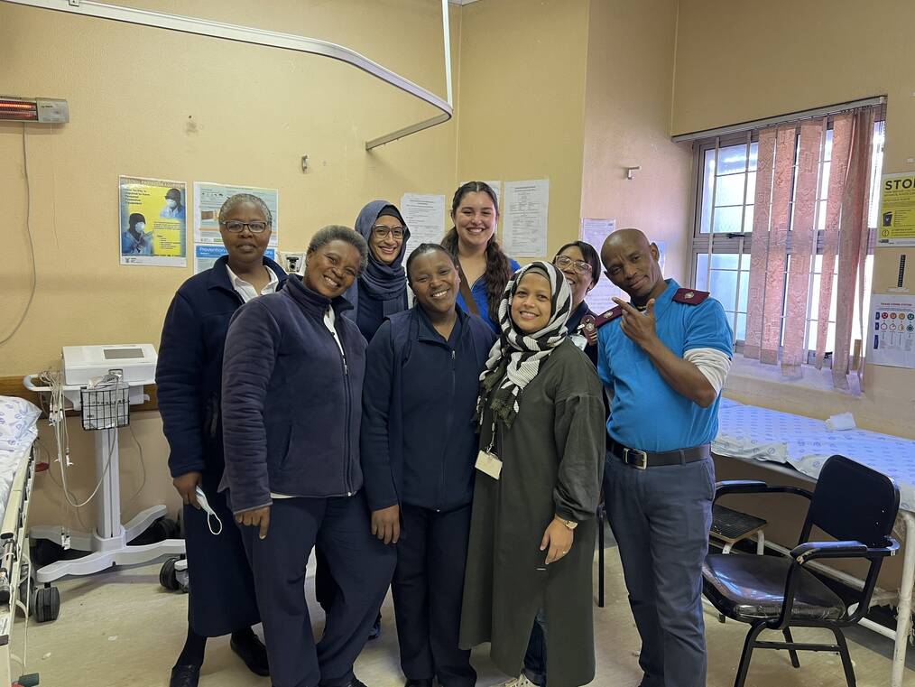 Intern in hospital room smiling with hospital staff while working with VA Corps