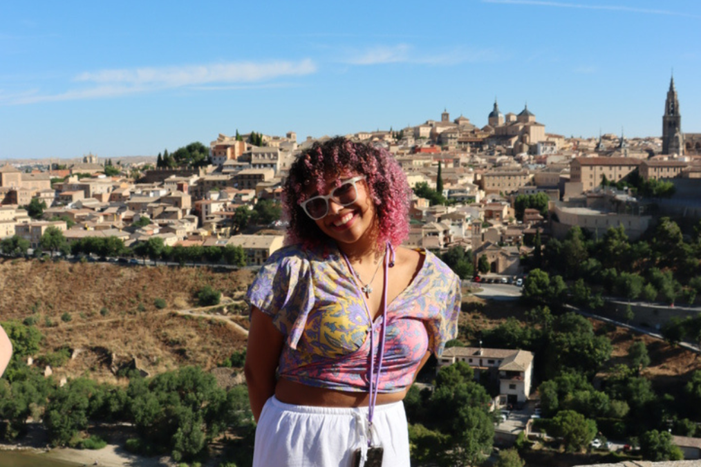 A woman smiles while overlooking Toledo, Spain, during her time with The Intern Group's Madrid program, with the historic cathedral and cityscape behind her