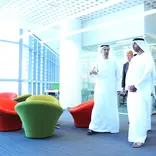 Khalifa University directors and leadership walk through the modern campus in traditional Arabic clothes. 