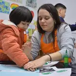 One of the alumni's from this program is pictured working with a student in China.