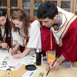 three young students writing Chinese characters with chinese brush in Chinese learning class