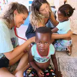 Two Volunteers doing a health screen of the children at the kindergarten