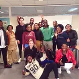15 Students standing in front of a white board looking happy
