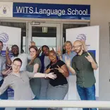 Group of teachers standing in front of a Wits Language School sign