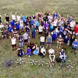 Students stand in a field with the drones they have just built and flown.
