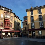 Two orange-toned, sunlit buildings with cafes at the bottom
