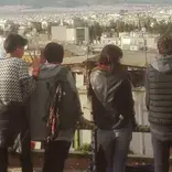 A group of students lined up a long a fence look at the view before them in Athens, Greece