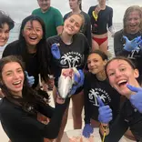 Group of teens on boat dissect fish