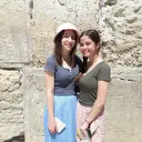 Two women stand in front of the Western Wall