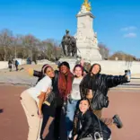 group of students pose in front of monument in london