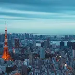 Panorama image a metropolis skyline with numerous high rises visible dwarfed by a tall red and white tower