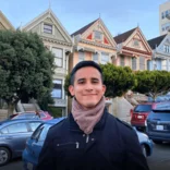 Young man poses in front of Painted Ladies in San Francisco