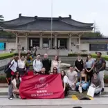 some stuments gathered in middle with a big red flag .background is a huge building
