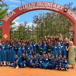 2023 volunteer group and students under SEGA School sign 