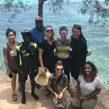 A group of students posing in front of a body of water.