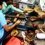 Three people making tools over coals