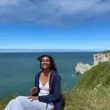 Student sitting on a hill overlooking a body of water, enjoying all that France has to offer