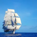 A tall ship with all sails up in the open ocean