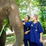 Two students in awe while touching an elephant