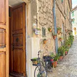 A quaint alleyway featuring a vintage bicycle leaning against a weathered door, capturing the essence of Spain and RVF International’s teach abroad adventure.