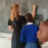 Volunteer teaching a class of eager students in a Tanzanian school