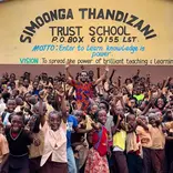 Volunteer cheering with children outside Simoonga. 